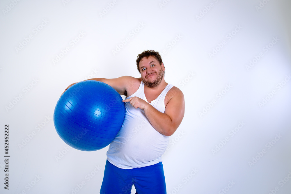 Funny fat man training with a fitness ball. Adult guy on a white background. Copy space. Active sports with a diet. Funny fat man training with a fitness ball. Adult guy on a white background. Copy space. Active sports with a diet.
