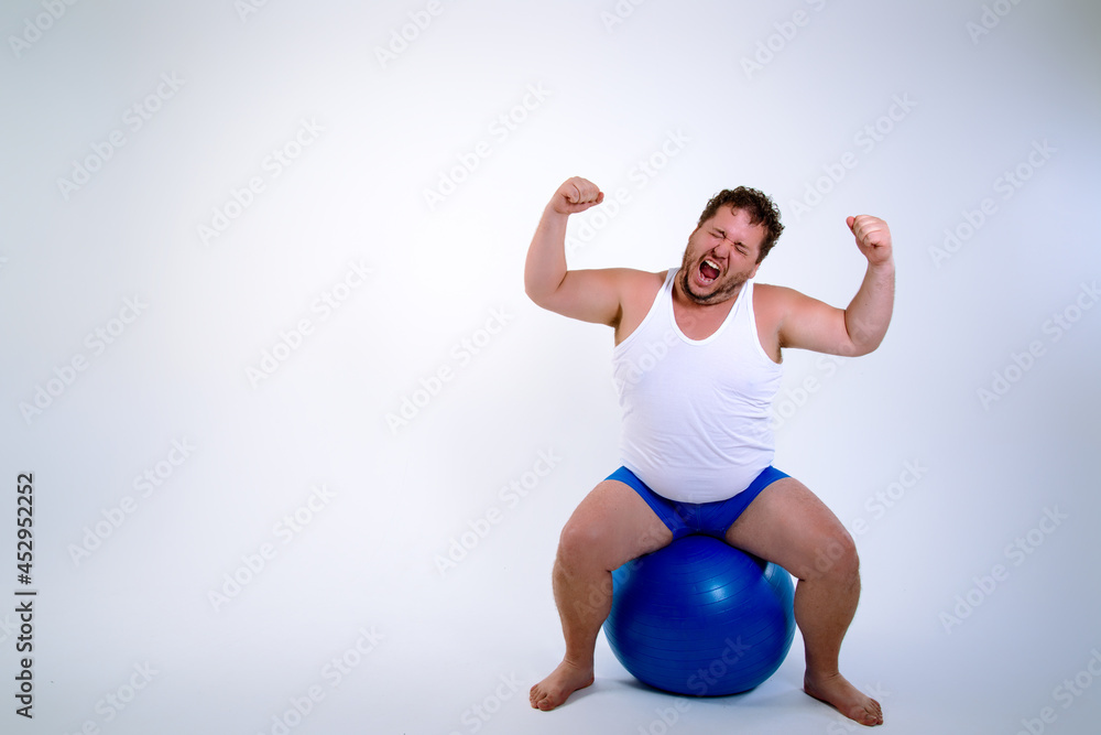 Funny fat man training with a fitness ball. Adult guy on a white background. Copy space. Active sports with a diet. Funny fat man training with a fitness ball. Adult guy on a white background. Copy space. Active sports with a diet.