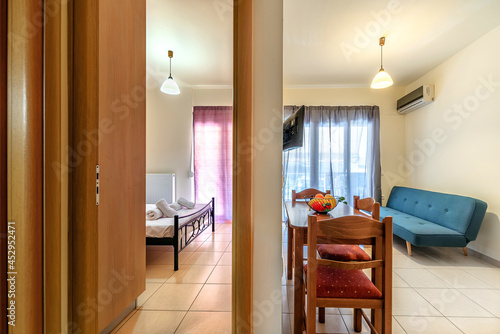 Fotografie Bedroom and separated living room with green blue sofa, dining table, chairs and air conditioning on the wall