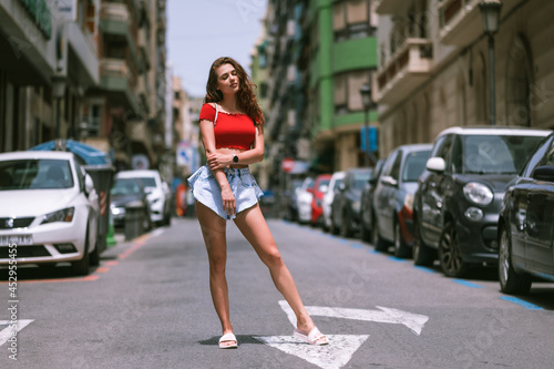 Obraz na plátne Fashion model posing outside in jeans shorts and red top.