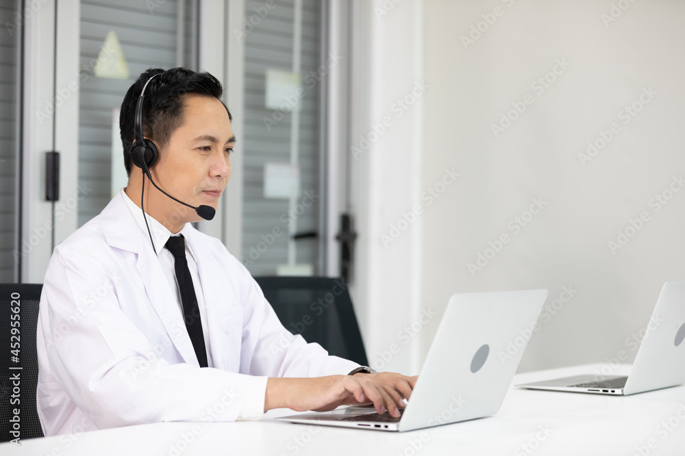 senior doctor wearing headphones and talking with patient or colleague through online video chat from laptop computer senior doctor wearing headphones and talking with patient or colleague through online video chat from laptop computer