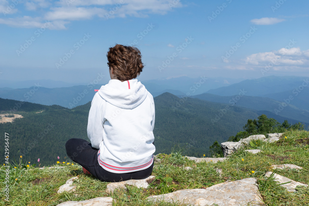 Close up image of young female in sport clothers seat on peak of green summer mountains, copy space. relaxation in beautiful nature.
