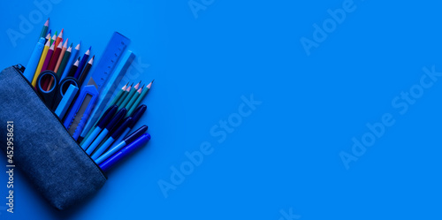 School pencil case and office supplies on a blue background. Preparation for school. Education concept. Place for your text.