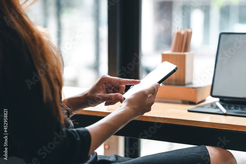 Close-up of a businesswoman hand holding a smartphone with a blank white screen working at the office.