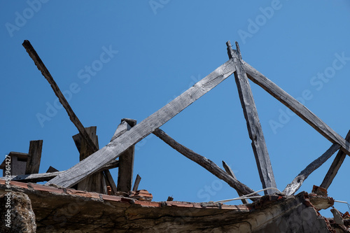 Remaining wooden beams from the roof of an old abandoned and ruined house. Rural abandonment concept