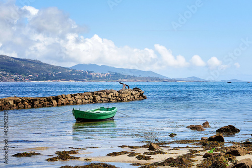 Schilderij op canvas Low tide with a traditional fishing rowboat in the Galician coast, Northern Spain