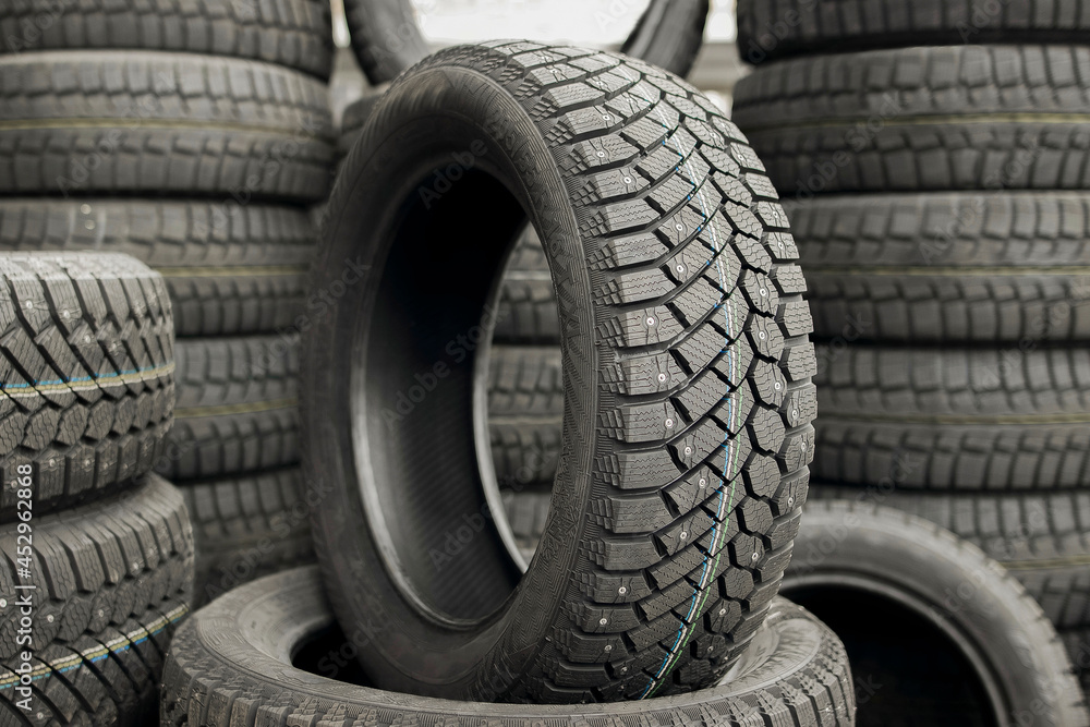 A new tire is placed on the tire storage rack in the car workshop. Car tires at warehouse in tire store.Stack of car tires on warehouse closeup.New car tyres stack.