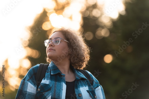 Front view of woman hiker standing outdoors in nature at sunset.