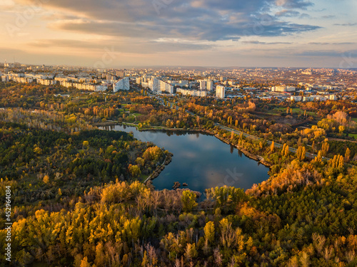 Obraz na płótnie Aerial view of a lake in a park with autumn trees. Kishinev, Moldova. Epic aerial flight over water. Colorful autumn trees in the daytime. w salonie
