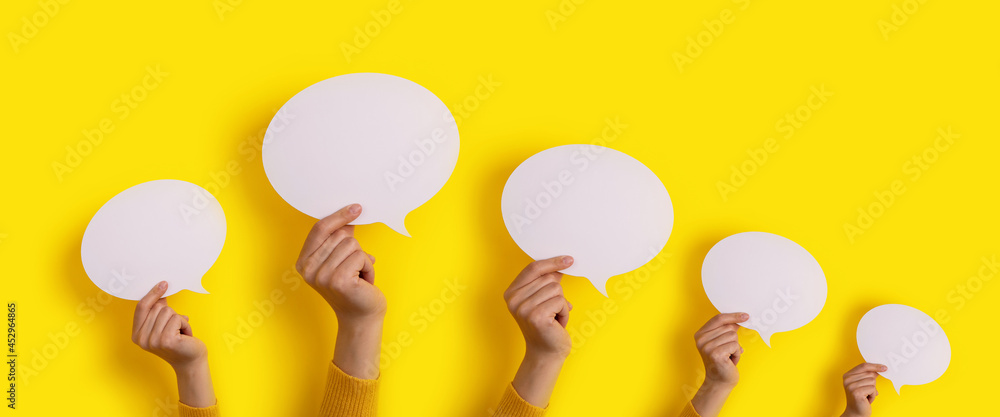 speech bubbles in hand over yellow background, panoramic layout over dialogue icon - obrazy, fototapety, plakaty 