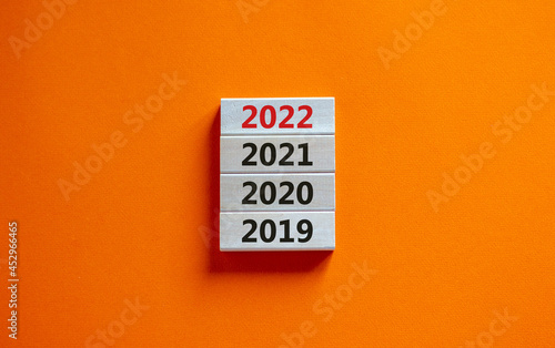2022 happy new year symbol. Wooden block with number '2022'. Stack with numbers '2019, 2020, 2021'. Beautiful orange background. Copy space. Business, 2022 happy new year concept.