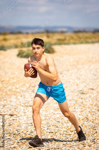 Fototapeta Naklejka Na Ścianę i Meble -  Running on a beach with an American Football