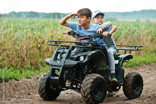 Two brothers driving four-wheller ATV quad bike. Happy children moments. photo