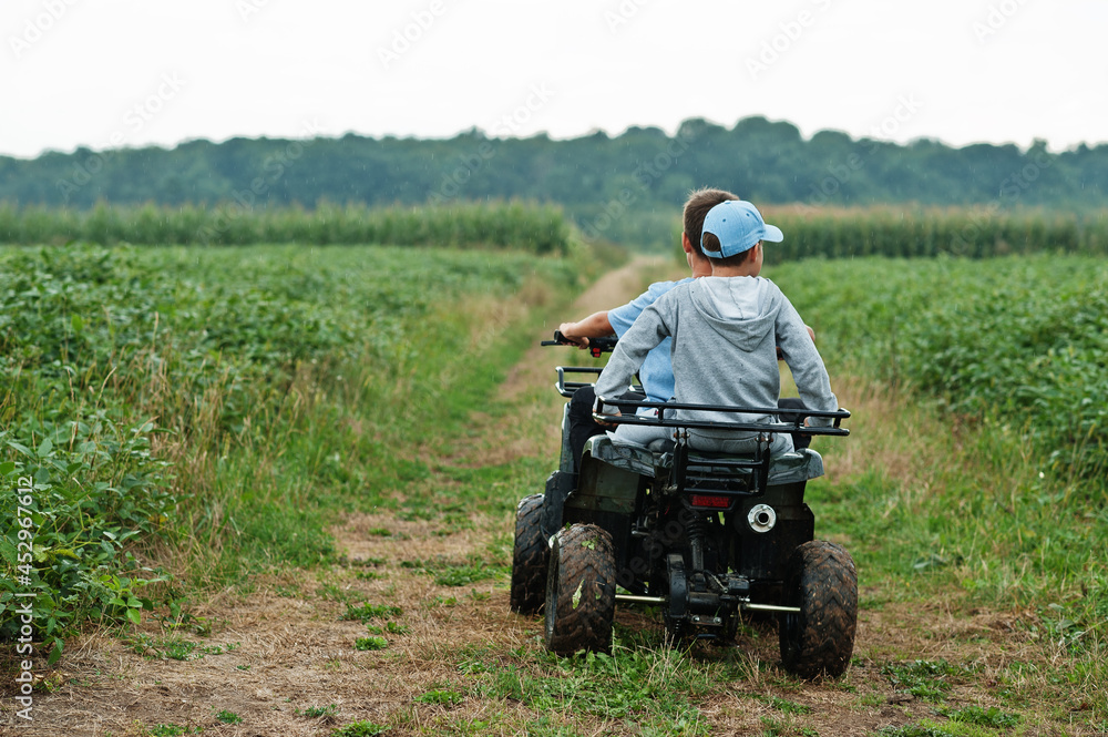 Two brothers driving four-wheller ATV quad bike. Happy children moments. Two brothers driving four-wheller ATV quad bike. Happy children moments.