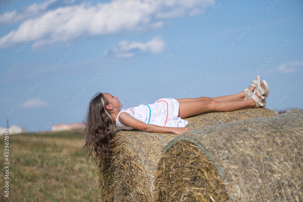 A beautiful girl plays in the field on bales of straw. A beautiful girl plays in the field on bales of straw.