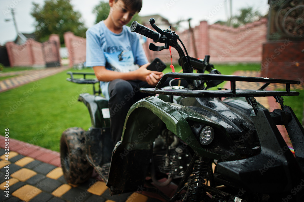 Boy in four-wheller ATV quad bike with mobile phone.