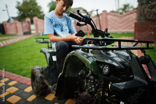 Boy in four-wheller ATV quad bike with mobile phone.