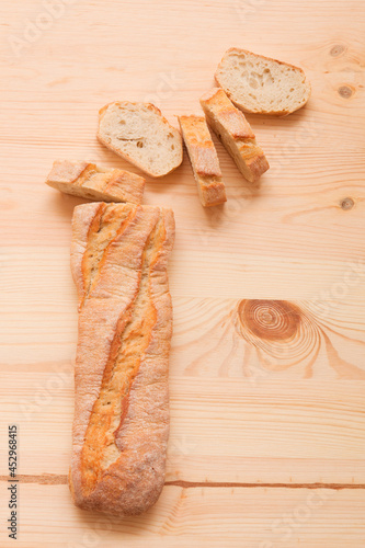 Sliced ​​baguette. Pieces of bread. Pastries on a light wooden background.