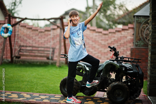 Boy in four-wheller ATV quad bike with mobile phone. photo