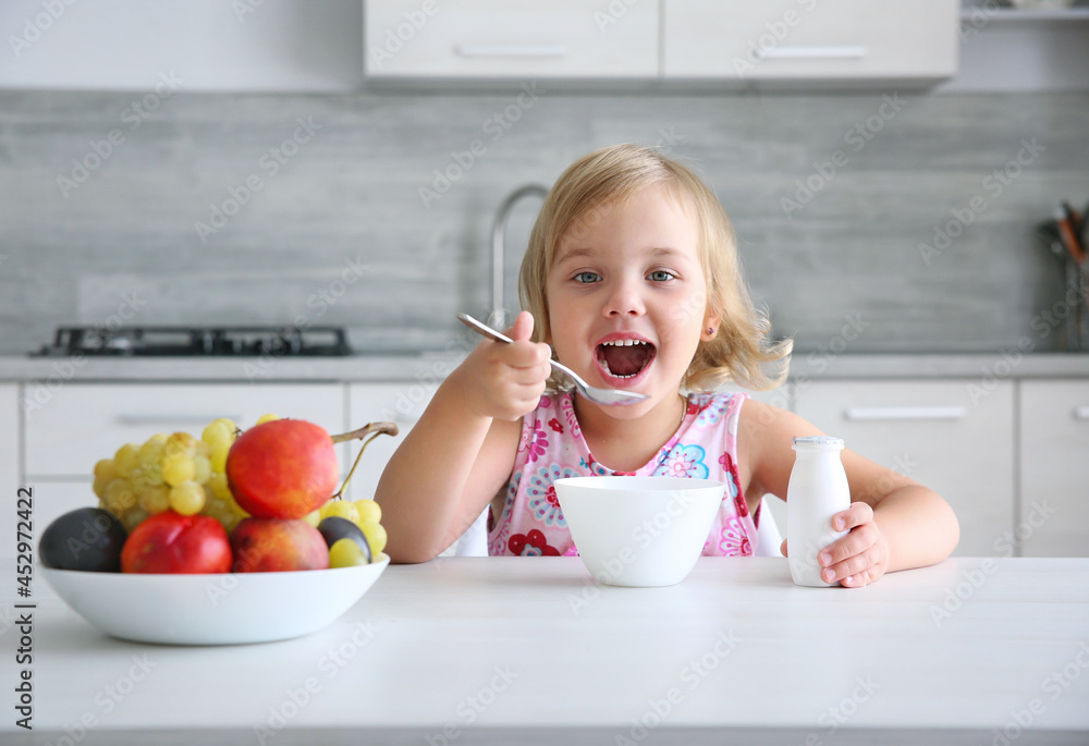 Child girl eating healthy food.Smiling little girl have a meal at kitchen.Kid have fruits and yogurt for lunch. Nutrition concept. Child girl eating healthy food.Smiling little girl have a meal at kitchen.Kid have fruits and yogurt for lunch. Nutrition concept.