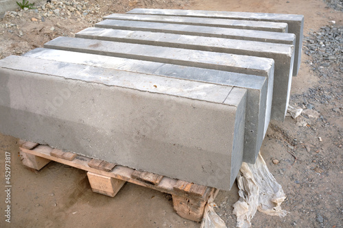 Photos Stack of gray curbstone on pallet standing on pavement