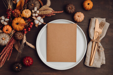 Rustic menu mockup with plate and autumn table decoration.  Floral interior decor for fall holidays with handmade pumpkins. Holiday dinner concept. Flatlay, top view.