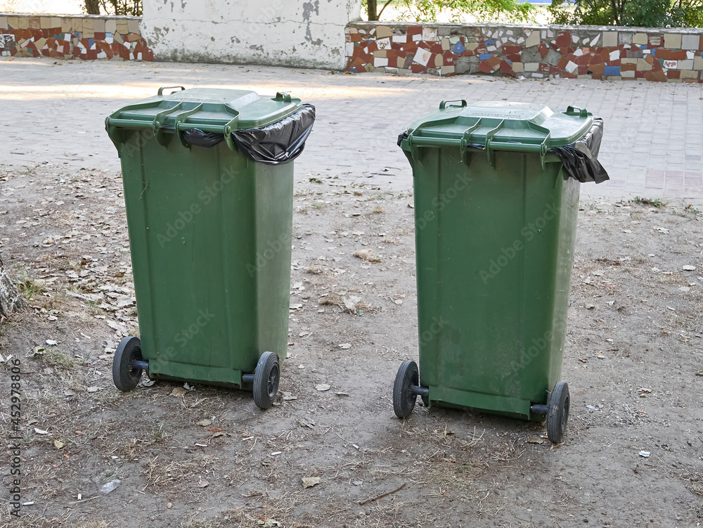 Two large green garbage containers on the street. Ecology and cleanliness in the city. Two large green garbage containers on the street. Ecology and cleanliness in the city.