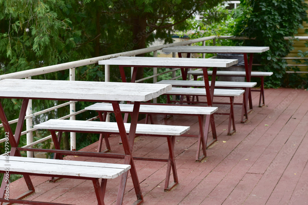 The picture shows the tables and benches of an open-air cafe. The picture shows the tables and benches of an open-air cafe.