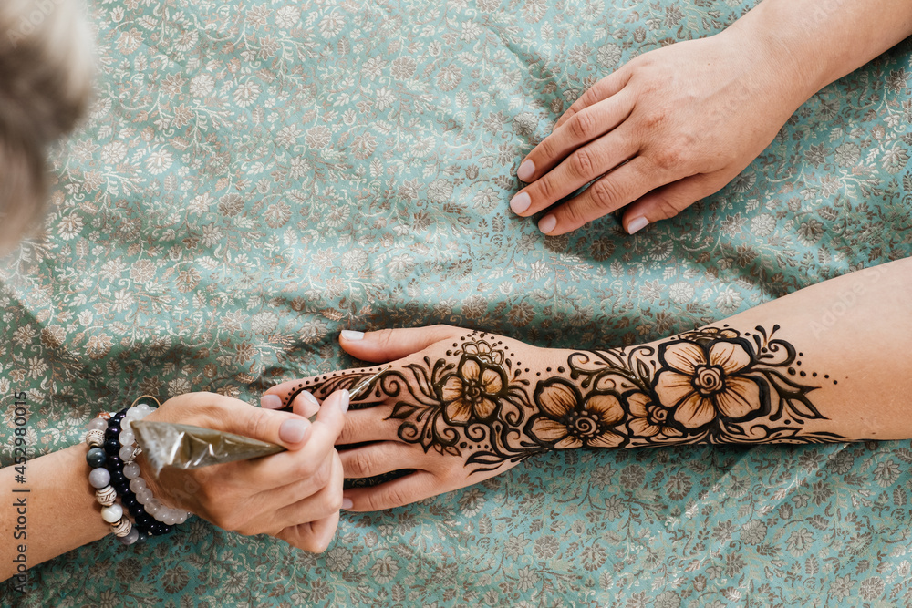Artist applying henna tattoo on women hands. Mehndi is traditional
