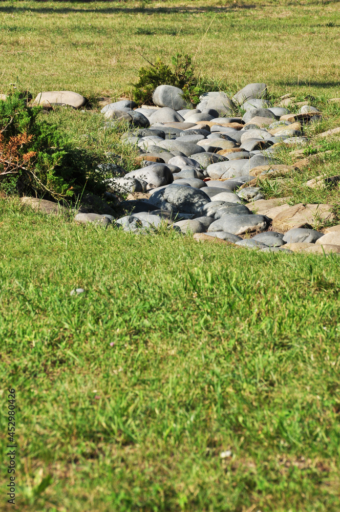 Landscaping. Large stones on the green grass. City square in Bryansk.