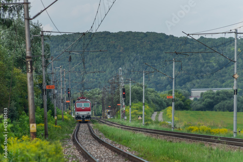 Passenger train with red electric locomotive and passenger coaches in summer