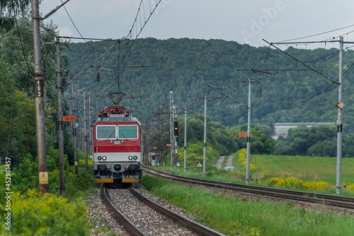 Passenger train with red electric locomotive and passenger coaches in summer photo
