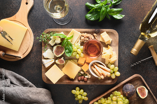 Photos Cheese platter with grapes, nuts, figs on a brown background