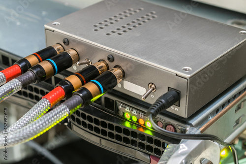 The AV cables are connected to a digital amplifier. The digital signal converter is in the rack. The multimedia equipment works in the server room. photo