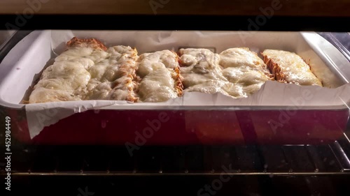 View on sandwiches in the oven while being grilled and the cheese are melting.