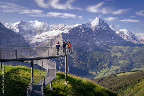 des touristes sur une passerelle dans le vide devant un panorama des alpes  photo