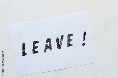 the expression "leave!" stencilled in black on white cards and arranged on a light background