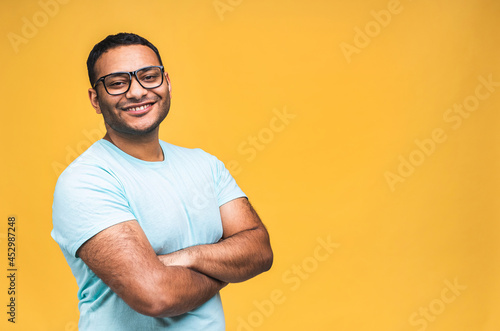 Portrait of a cheerful young african american indian black man standing isolated over yellow background.
