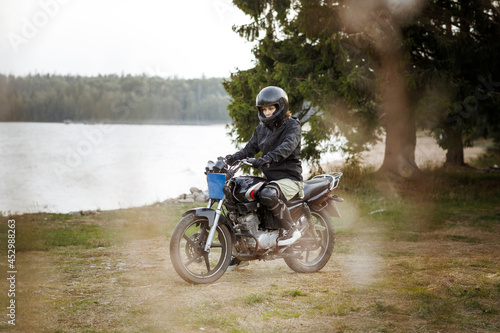 a woman on a motorcycle in nature. motorcyclist walk through the forest