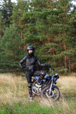 a woman on a motorcycle in nature. motorcyclist walk through the forest