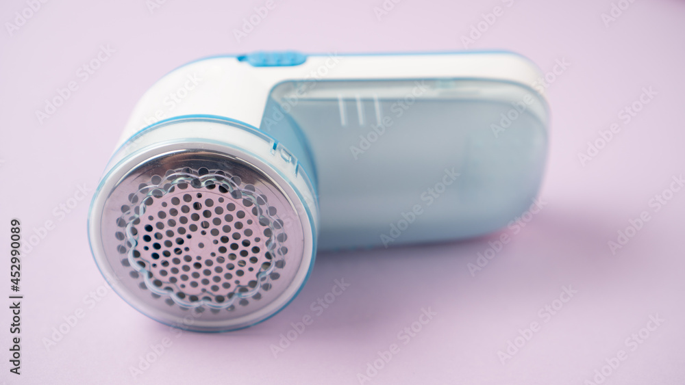 Small fabric shaver on purple background. Handed lint remover. Clothes shaver device Small fabric shaver on purple background. Handed lint remover. Clothes shaver device