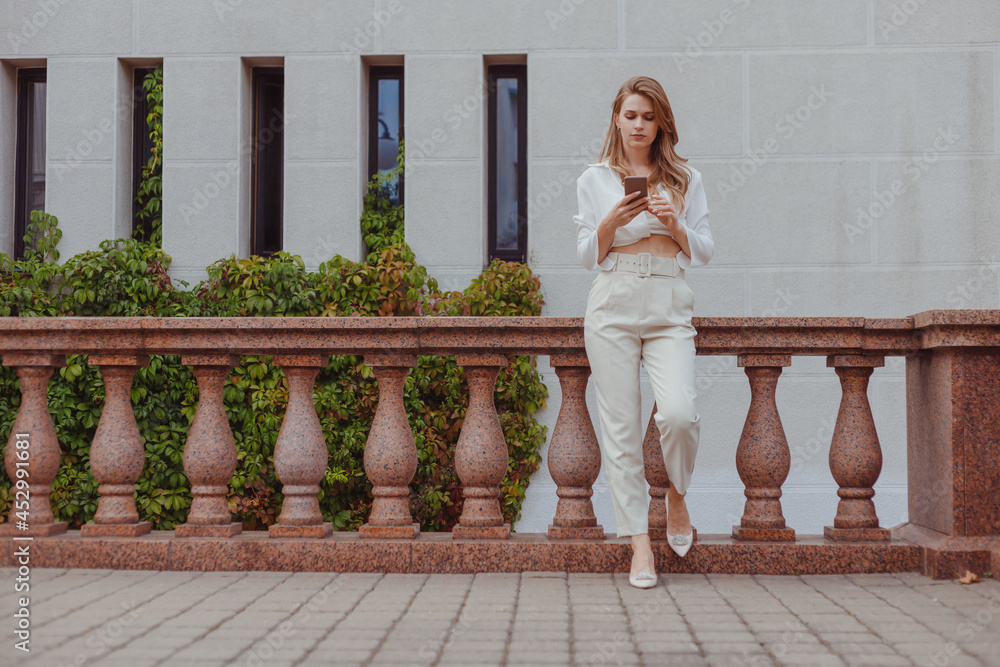 Young in white look using smartphone in the city, texting message, connect