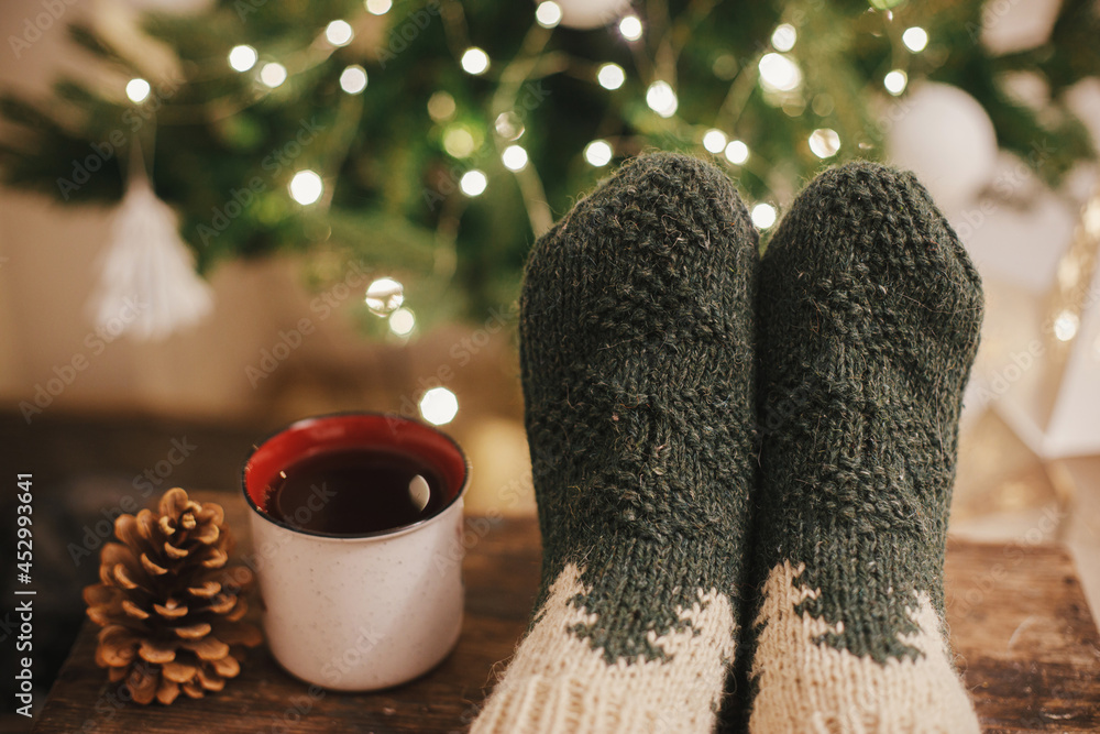 Cozy winter moments at home. Woman feet in cozy woolen socks and cup of  warm tea