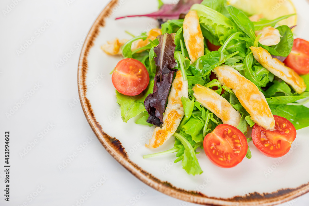 delicious Caesar salad with rucola leaves, cherry tomatoes and chicken fillet on a plate in a restaurant