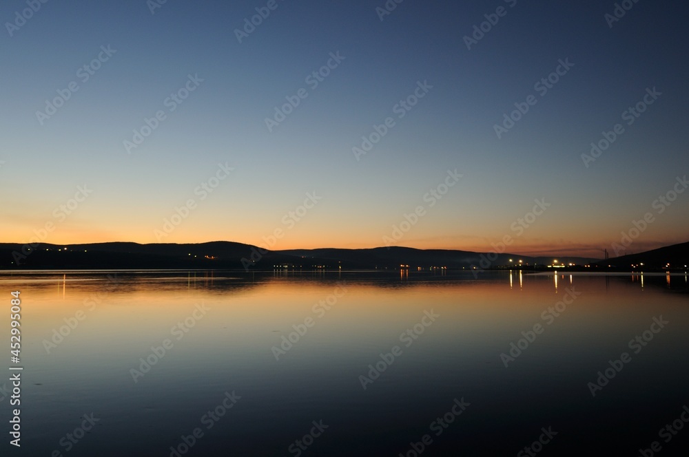 Evening view of the Kola Bay Murmansk is the main port in the north of Russia. Beautiful sunset with the reflection of the lights in the bay. Beautiful landscape on the side of Cape Abram.