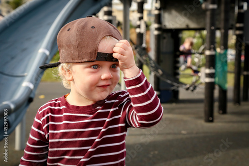 Spunky toddler boy at the playground wearing hat backwards photo