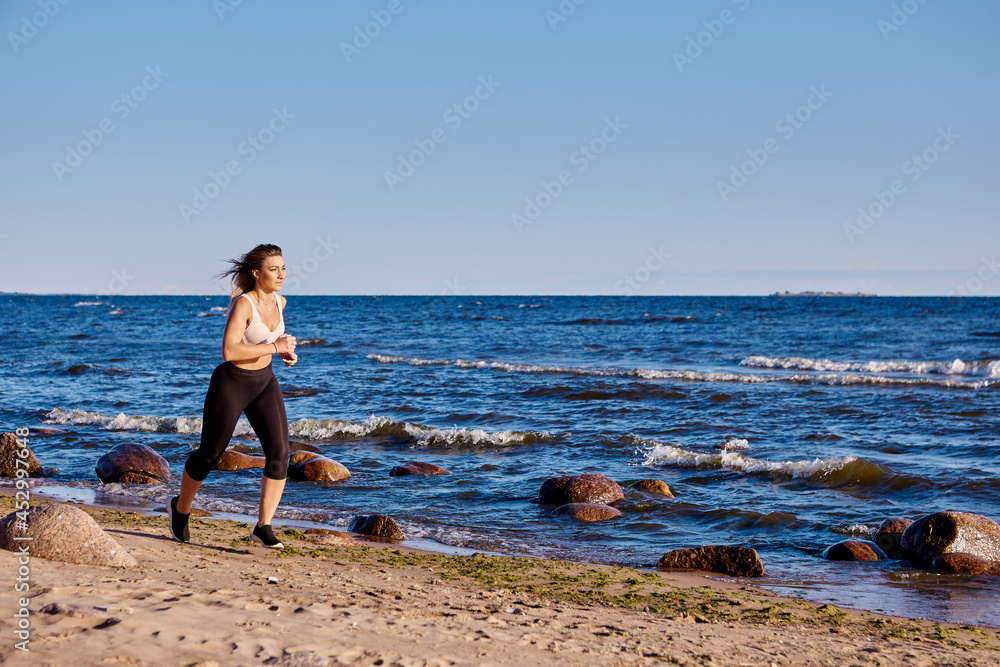 Woman in sportswear is running near shore.