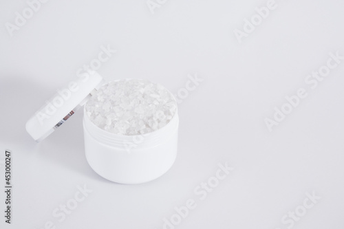Blank white jar with bath salt on gray background, cosmetic mock up