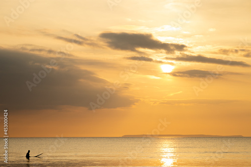 Silhouette of a surfer in the sea waiting for waves with a background of the sunset