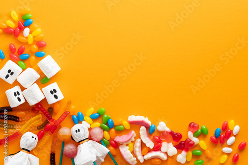 Happy halloween holiday concept. Halloween decorations and candies on orange background. Halloween party greeting card mockup with copy space. Flat lay, top view, copy space.